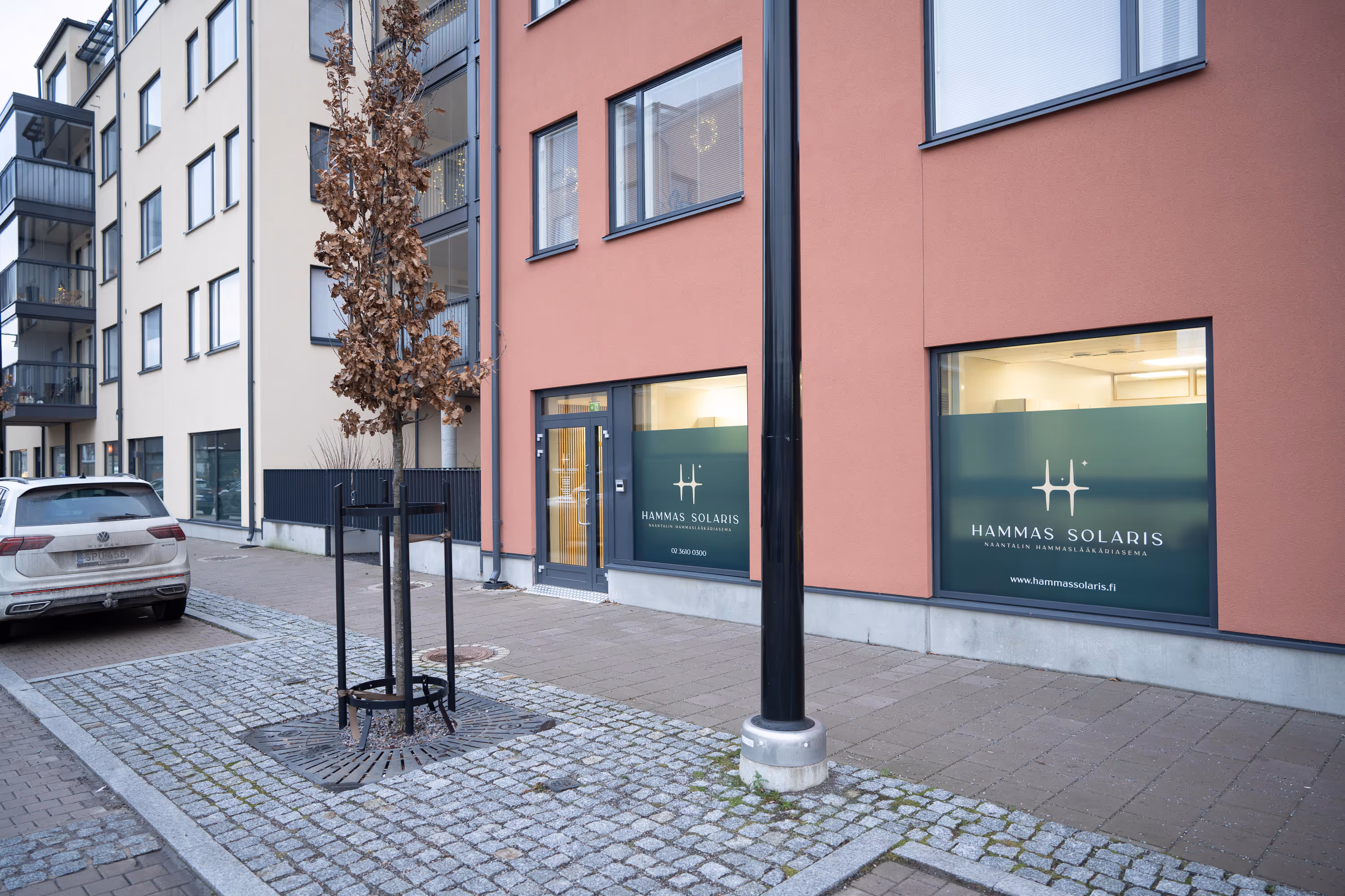 Hammaslääkäri Naantalissa, jonka ikkunoissa on "HAMMAS SOLARIS" -logo, sekä vaalea rakennus, jonka parvekkeet ovat lasitettuja.